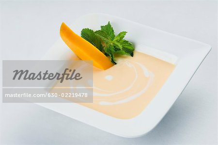 Schale mit Creme mit Mango-Slices und Minze