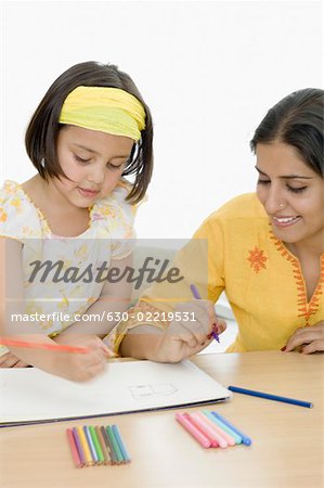Young woman with her daughter coloring on a coloring book