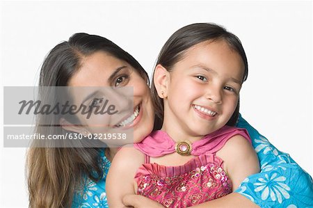 Portrait d'une jeune femme embrassant sa fille par derrière et souriant