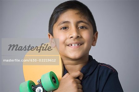 Portrait of a boy holding a skateboard and smiling