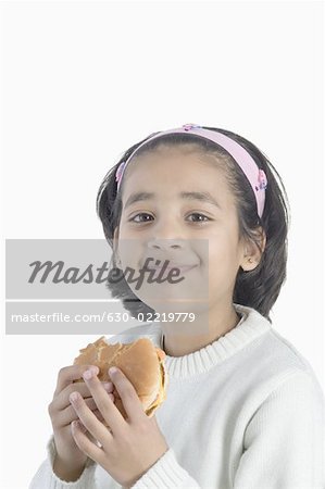 Portrait d'une jeune fille manger un hamburger