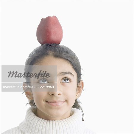 Girl balancing an apple on her head and smiling