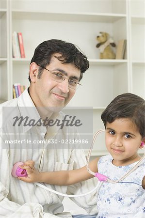 Portrait d'une jeune fille examinant son père avec un stéthoscope