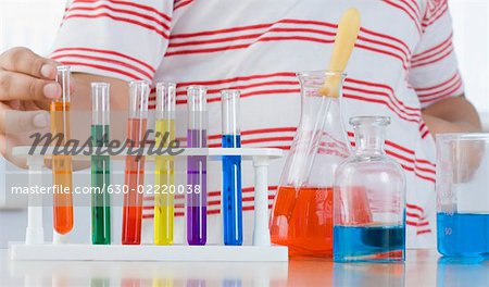 Mid section view of a boy putting a test tube in a test tube holder