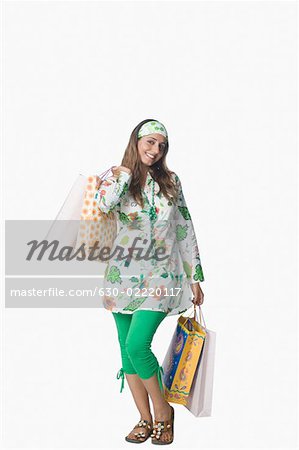 Portrait d'une jeune femme tenant des sacs à provisions et souriant