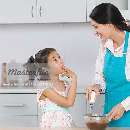 Mid adult woman preparing food in the kitchen with her daughter