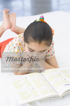 Mädchen auf dem Bett liegen und ein Buch zu lesen