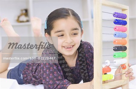 Girl lying on the bed and playing with an abacus