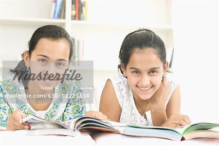 Portrait of a teenage girl lying with her sister and studying