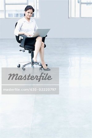Porträt einer geschäftsfrau, die mit einem Laptop in einem Büro