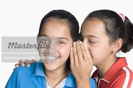 Girl whispering into her sister's ear