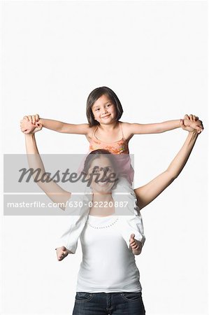Porträt einer jungen Frau mit ihrer Tochter auf ihren Schultern und Lächeln