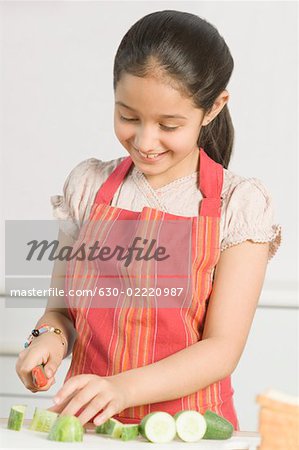 Close-up of a girl cutting cucumber with a knife