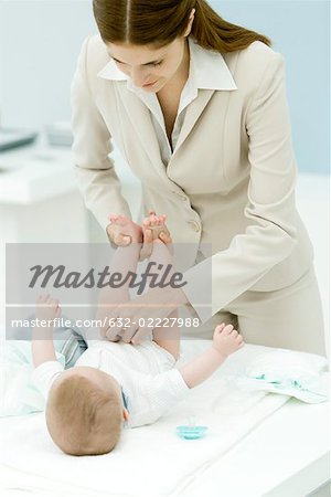 Professional woman changing baby's diaper on desk