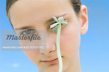 Girl with long stemmed succulent plant obscuring one of her eyes