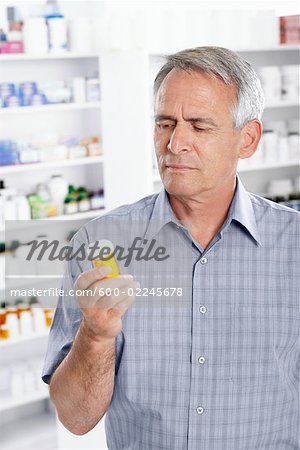 Man in Pharmacy Looking at Bottle of Pills