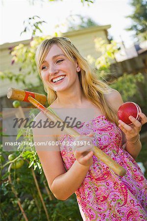 Woman in Backyard with Croquet Mallet and Ball, Portland, Oregon, USA