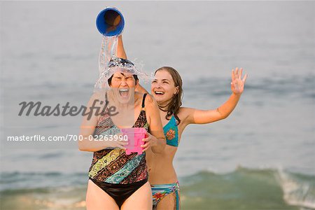 Fille verser le seau d'eau sur la tête de la mère à la plage, dans le New Jersey, USA