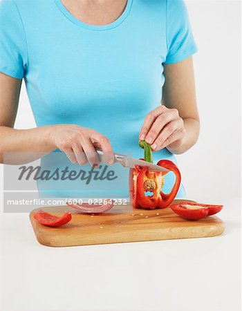 Femme couper le poivron rouge