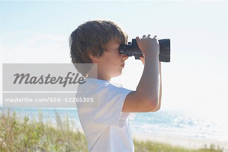 Boy on the Beach Looking Through Binoculars, Elmvale, Ontario, Canada