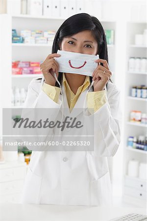 Apotheker, die ein Stück von Papier mit ein Lächeln gezeichnet auf hält es über ihr Gesicht