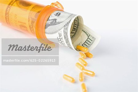 Roll of US one hundred dollar bills inside a pill bottle with capsule