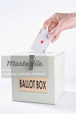 Person's hand inserting a playing card into a ballot box