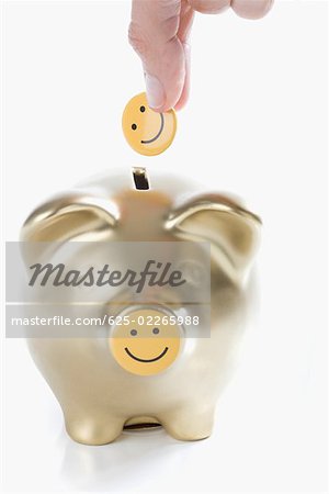 Close-up of a person's hand putting a smiley face into a piggy bank