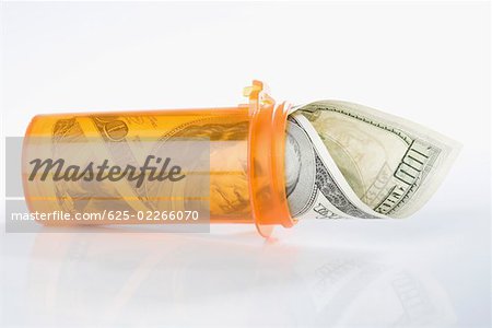 Roll of US one hundred dollar bills inside a pill bottle