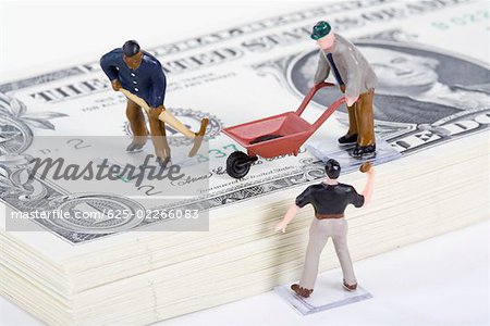 Figurines of manual workers with US paper currency