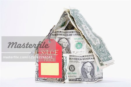 Plaquette de vente placée avec une maison miniature composée de billets d'un dollar US
