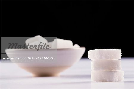 Stack of sugar cubes and a bowl of sugar cubes in the background