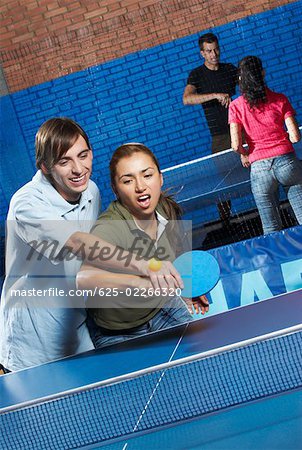 Young man teaching table tennis to a young woman