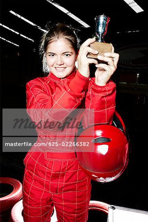 Porträt einer weiblichen Gokart Racer holding eine Trophäe und Lächeln