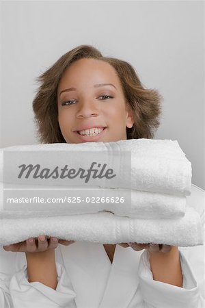 Portrait d'une jeune femme tenant une pile de serviettes pliées et souriant