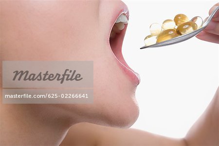 Close-up of a young woman taking a spoon full of pills