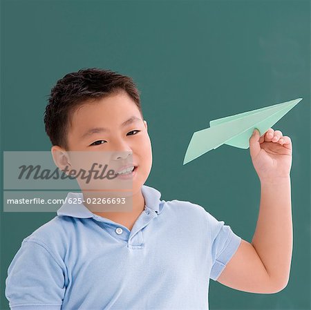 Gros plan d'un garçon tenant un avion en papier