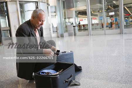 Seitenansicht eines Unternehmers, der seine Koffer packen, an einem Flughafen