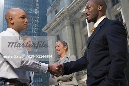 Seitenprofil von zwei Geschäftsleuten Händeschütteln mit zwei Geschäftsfrauen lächelnd
