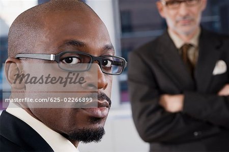 Portrait d'un homme d'affaires pensant avec un autre homme d'affaires permanent en arrière-plan