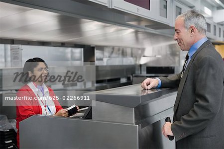 Side profile of a businessman standing at a ticket counter in an airport