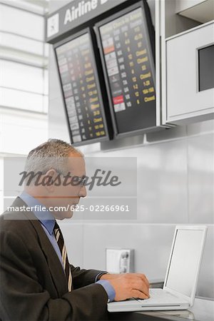 Seitenansicht eines Unternehmers mit einem Laptop an einem Flughafen Check-in Schalter