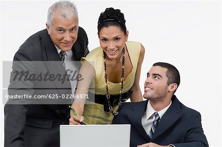 Two businessmen and a businesswoman discussing on a laptop in an office