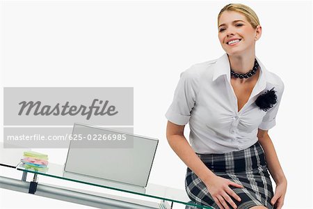 Femme d'affaires assis sur une table et souriant