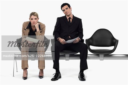 Businessman and a businesswoman sitting on a bench