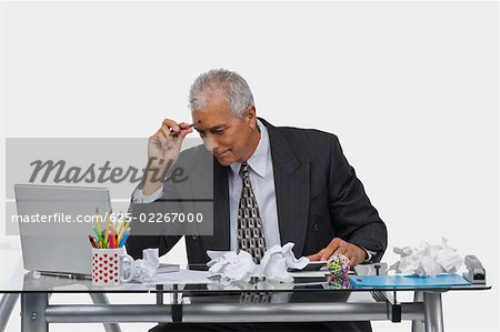 Homme d'affaires assis derrière un bureau avec des papiers froissés sur le bureau