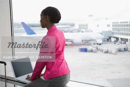 Side profile of a businesswoman using a laptop at an airport