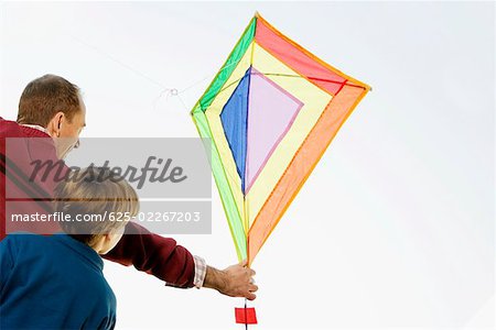 Rear view of a mid adult man with his son flying a kite
