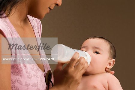 Close-up of a young woman feeding her son with a baby bottle