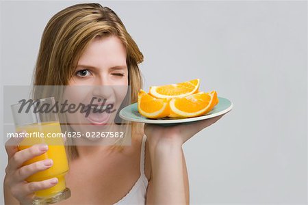 Portrait d'une adolescente qui maintiennent une plaque d'oranges et un verre de jus d'orange